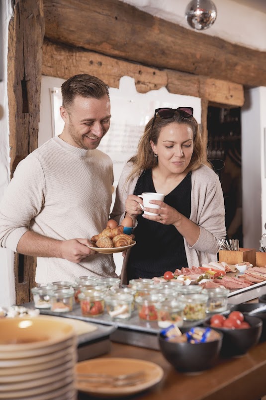 Paar genießt das reichhaltige Frühstücksbuffet im historischen Fachwerkhaus des Weinforum Franken