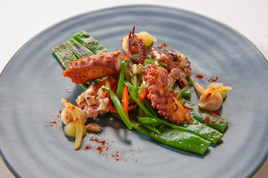 Gegrillter Oktopus mit Schnittlauch und Paprika auf blauem Teller – mediterraner Genuss im Restaurant Weinforum Franken